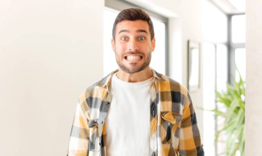 Yakışıklı adam mutlu ve şapşal görünüyor. Geniş, eğlenceli, deli gülüşü ve gözleri açık.