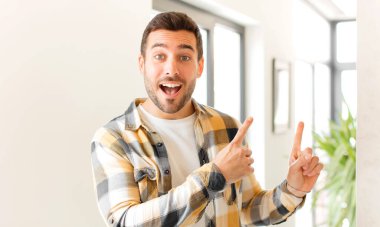 Yakışıklı adam mutlu bir şekilde gülümsüyor ve her iki elinde fotokopi uzayında nesne gösteriyor.