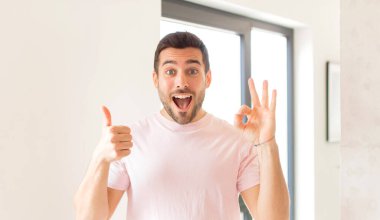Yakışıklı adam kendini mutlu, şaşkın, tatmin olmuş ve şaşırmış hissediyor.