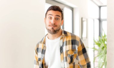 Yakışıklı bir adam şapşal, çılgın, şaşırmış bir ifadeyle, yanakları şişmiş, doldurulmuş, şişman ve yemekle dolu