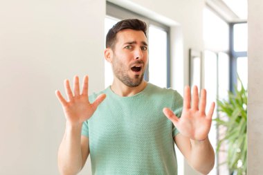 Yakışıklı adam sersemlemiş ve korkmuş hissediyor. Korkutucu bir şeyden korkuyor. Elleri açık ve uzak dur diyor.