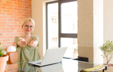 Güzel öğrenci mutlu bir şekilde gülümsüyor, kendine güvenen, olumlu bakışlı, bir nesne ya da konsept sunuyor ve gösteriyor.