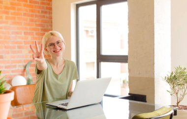 Güzel bir öğrenci gülümsüyor ve arkadaş canlısı görünüyor. Üç ya da üç numarayı gösteriyor. Elleri önde, geri sayıyor.