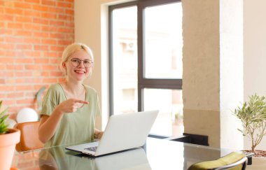 Güzel öğrenci heyecanlı ve şaşırmış görünüyor. Yana ve yukarı doğru uzayı gösteriyor.