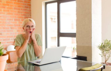 Güzel öğrenci şok olmuş ve korkmuş hissediyor, ağzı açık ve elleri yanaklarında korkmuş görünüyor.