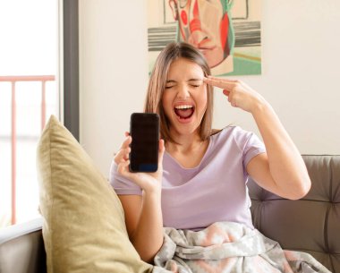 Güzel bir kadın mutsuz ve stresli görünüyor, intihar jesti elle silah işareti yapıyor, kafasını işaret ediyor.