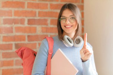 Güzel öğrenci gururla gülümsüyor ve gururla bir numaralı poz veriyor, kendini lider gibi hissediyor.
