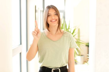 Güzel bir kadın gülümsüyor ve arkadaş canlısı görünüyor. Bir numarayı gösteriyor ya da ilk eli önde, geri sayıyor.