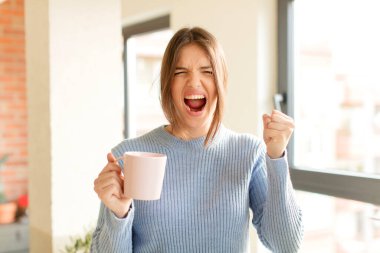 Güzel bir kadın öfkeli bir ifadeyle ya da yumruklarıyla başarıyı kutlarken agresif bir şekilde bağırıyor.