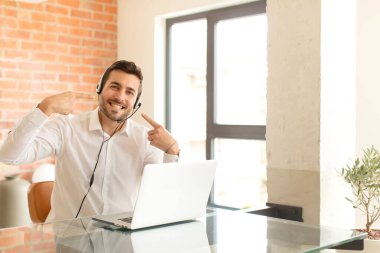 Yakışıklı pazarlamacı kendine güvenerek gülümsüyor. Geniş bir gülümseme, pozitif, rahat, tatmin olmuş bir tavır sergiliyor.