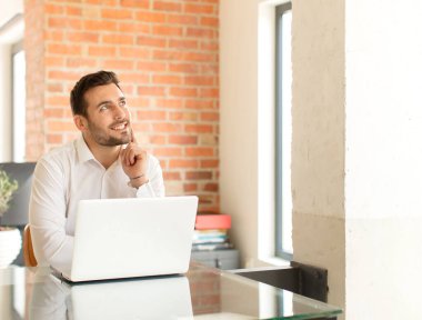 Yakışıklı işadamı mutlu bir şekilde gülümsüyor ve hayal kuruyor ya da şüphe ediyor.