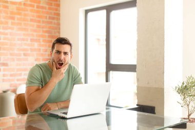 Ağzı ve gözleri açık, eli çenesinde olan yakışıklı bir adam, nahoş bir şekilde şokta, ne ya da vay canına diyor.