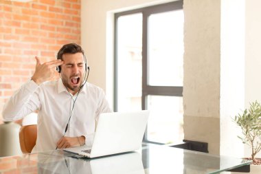 Yakışıklı pazarlamacı mutsuz ve stresli görünüyor, intihar jesti elle silah işareti yapıyor, kafasını işaret ediyor.