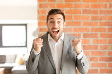 Yakışıklı iş adamı şaşkın, heyecanlı ve mutlu hissediyor, gülüyor ve başarıyı kutluyor,!