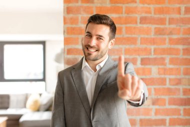 Yakışıklı işadamı gururla gülümsüyor ve bir numaralı pozunu başarıyla veriyor, kendini lider gibi hissediyor.