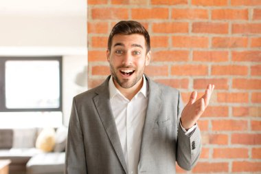 Yakışıklı iş adamı kendini mutlu, şaşkın ve neşeli hisseder. Pozitif bir tavırla gülümser. Bir çözüm ya da fikri fark eder.