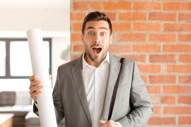 Yakışıklı mimar şaşkın ve şaşkın hissediyor, şüpheci, farklı seçenekleri tartıyor veya komik bir ifadeyle seçiyor