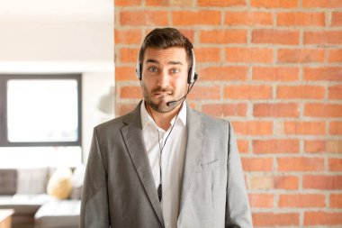 Yakışıklı pazarlamacı şaşkın ve kafası karışık görünüyor. Sinirli bir hareketle dudağını ısırıyor. Sorunun cevabını bilmiyor.