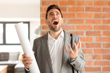 Yakışıklı mimar umutsuz ve sinirli görünüyor, stresli, mutsuz ve sinirli, bağırıyor ve çığlık atıyor.