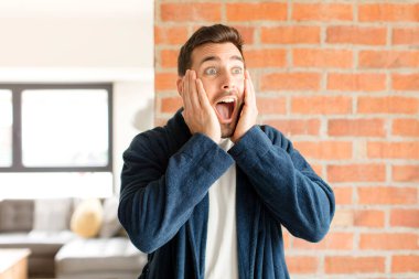 Yakışıklı adam mutlu, heyecanlı ve şaşırmış hissediyor, iki eli yüzü yana bakıyor.