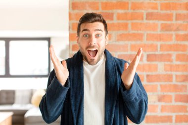 Yakışıklı adam mutlu, heyecanlı, şaşırmış ya da şaşırmış, gülümseyen ve hayrete düşmüş.