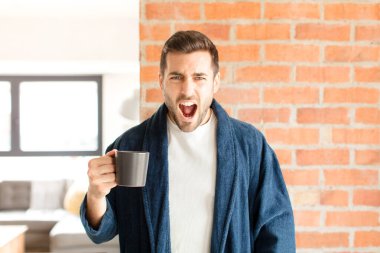 Yakışıklı adam agresif bir şekilde bağırıyor, sinirli, sinirli, öfkeli ya da sinirli görünüyor.