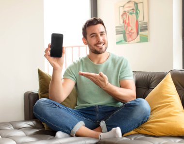 Yakışıklı bir adam neşeyle gülümsüyor, mutlu hissediyor ve fotokopi uzayda avucunun içinde bir konsept gösteriyor.