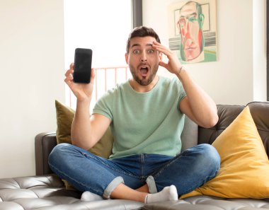 Yakışıklı adam mutlu, şaşkın ve şaşırmış görünüyor, gülümsüyor ve inanılmaz ve inanılmaz iyi haberleri fark ediyor.