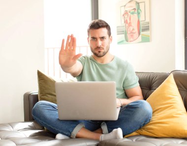 Yakışıklı adam ciddi, sert, hoşnutsuz ve kızgın görünüyor. Avuç içini açıp jesti durduruyor.