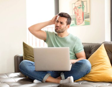 Yakışıklı adam şaşkın ve şaşkın hissediyor, başını kaşıyor ve yana bakıyor.