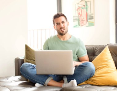 handsome man feeling puzzled and confused, with a dumb, stunned expression looking at something unexpected