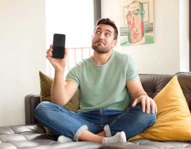 Yakışıklı adam omuz silkiyor, şaşkın ve kararsız hissediyor, kolları bağlı ve şaşkın bir şekilde şüpheye düşüyor.