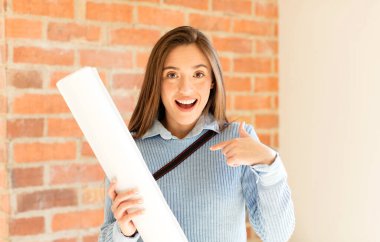 Güzel mimar mutlu, şaşırmış ve gururlu hissediyor, heyecanlı ve şaşkın bir bakışla kendini işaret ediyor.