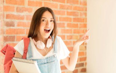 Heyecanlı ve şaşırmış görünüyor. Yana ve yukarıya bakıyor. Boşluğu kopyalıyor.