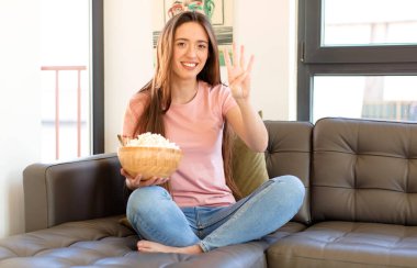 Gülümsüyor ve dost canlısı görünüyor, 4 ya da 4 numarayı gösteriyor, elle ileri doğru, geri sayıyor.