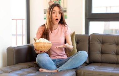 Şaşırmış ve şoke olmuş bir halde, çenesi düşmüş bir objeyi elinde açık bir elle tutarken.