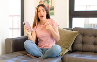 Şok olmuş ve ağzı açık, kendini işaret eden güzel bir kadın.