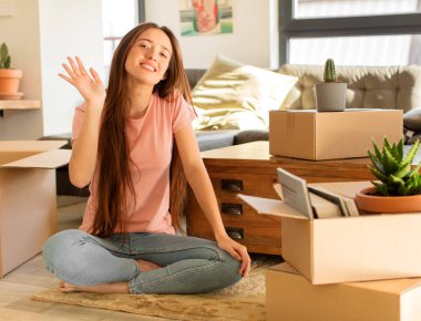 Güzel bir kadın mutlu ve neşeyle gülümsüyor, el sallıyor, seni selamlıyor ve selamlıyor, ya da hoşça kal diyor.