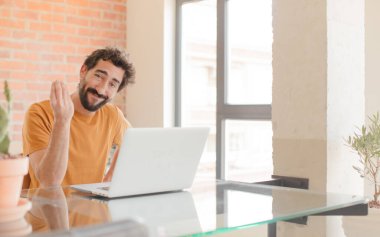 Genç sakallı adam sana borcunu ödemeni söyleyerek kapiş ya da para hareketi yapıyor! Ve bir dizüstü bilgisayarla çalışmak.