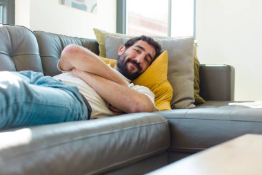 Genç sakallı adam kanepede dinleniyor.