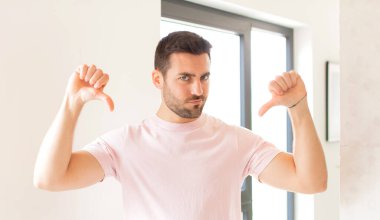 Yakışıklı bir adam üzgün, hayal kırıklığına uğramış ya da kızgın görünüyor, anlaşmazlık içinde başparmaklarını gösteriyor, hayal kırıklığına uğramış hissediyor.