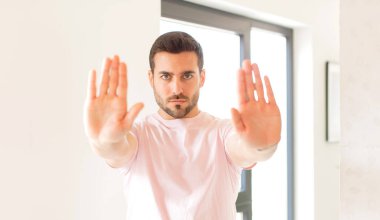 Yakışıklı adam ciddi görünüyor, mutsuz, kızgın ve hoşnutsuz giriş yasaklandı ya da her iki avuçta da dur diyor.