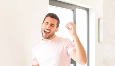 Yakışıklı adam gülümsüyor, kaygısız hissediyor, rahat ve mutlu, dans ediyor ve müzik dinliyor, bir partide eğleniyor.