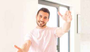 Yakışıklı adam neşeyle gülümsüyor sıcak, dostça, sevgi dolu bir kucaklama yapıyor, mutlu ve sevimli hissediyor.