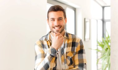 Yakışıklı adam gülümsüyor, hayattan zevk alıyor, mutlu, arkadaş canlısı, tatmin olmuş ve tasasız.