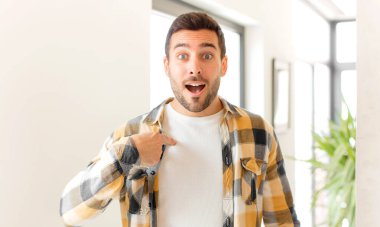 Yakışıklı adam mutlu, gururlu ve şaşırmış görünüyor, neşeli bir şekilde kendini gösteriyor, kendinden emin ve yüce hissediyor.