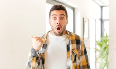 Yakışıklı adam inançsızlıktan şaşkın şaşkın bakıyor, yan taraftaki objeyi işaret ediyor ve diyor ki: