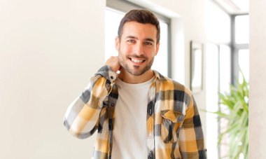 Yakışıklı adam neşeli ve kendinden emin bir şekilde gülüyor. Sıradan, mutlu, dostane bir gülümsemeyle.