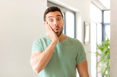 Yakışıklı adam şok olmuş ve ağzı açık bir şekilde yüz yüze inanamamaktan şaşkına dönmüş durumda.