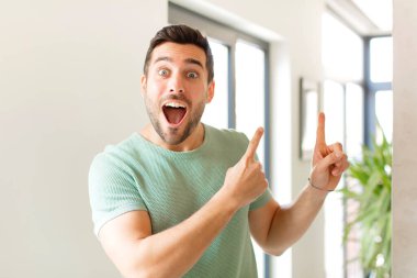 Yakışıklı adam mutlu ve şaşırmış hissediyor, şok olmuş bir ifadeyle gülümsüyor ve bir tarafı işaret ediyor.